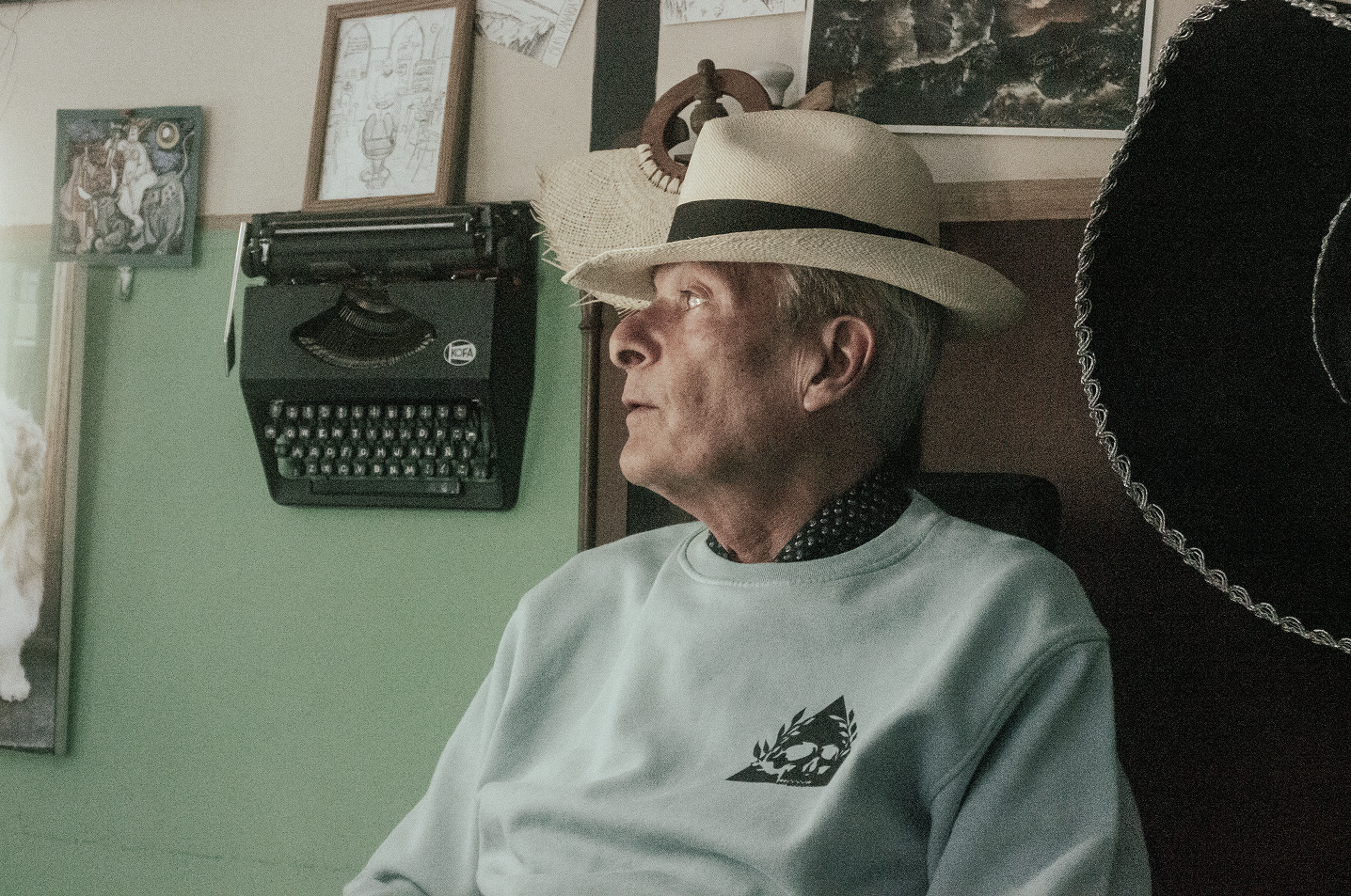 An old man wearing Canary Famous shirt in a cafe.